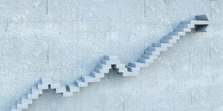 Karriere_Stufen Aus einer grauen Wand ragen Stufentreppen hervor.